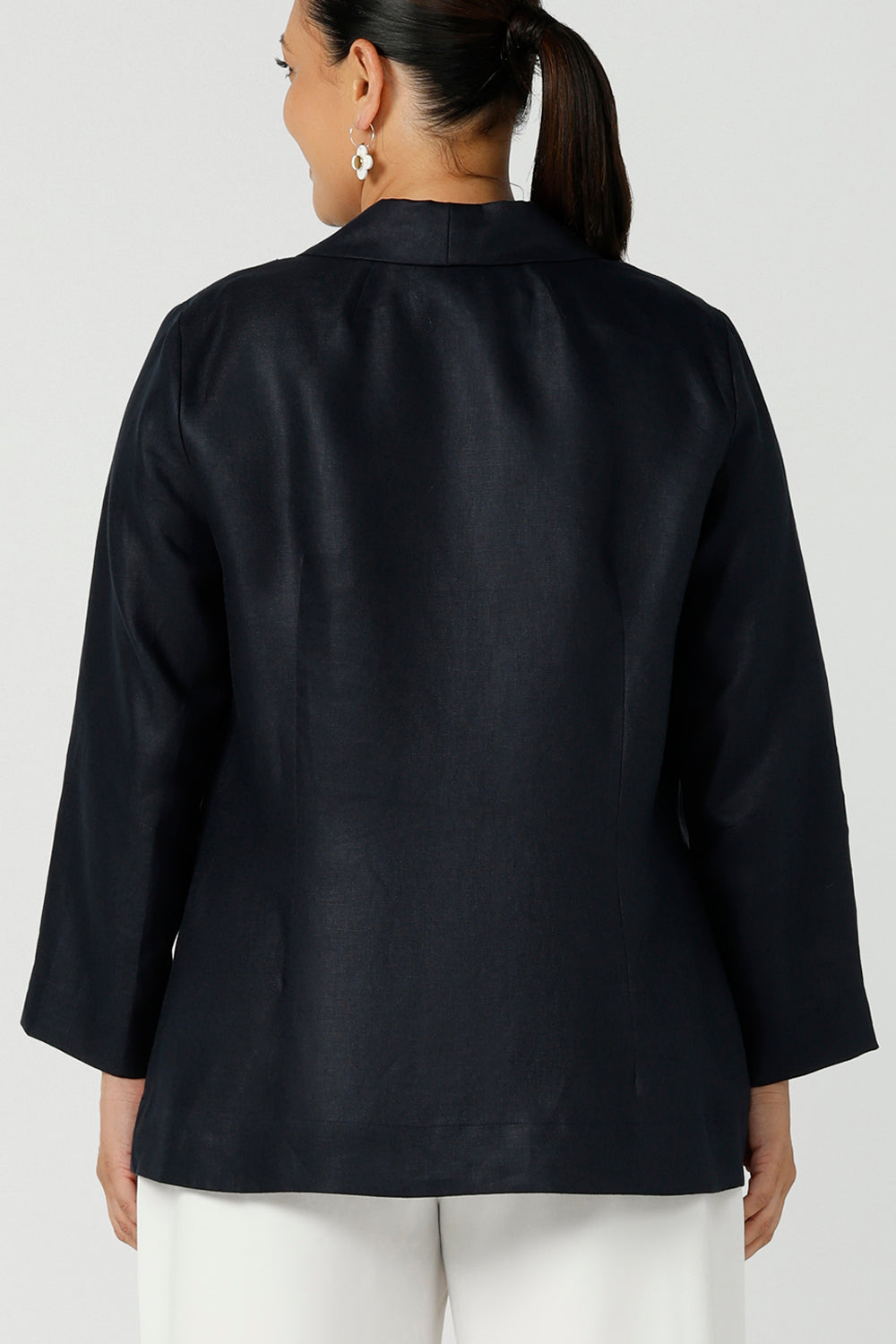 Back view of a size 12 woman wearing a soft linen blazer jacket with a tailored design. A transeasonal linen work jacket, in a beautiful midnight navy colour. Australian-made using sustainable 100% linen fabric. Size-inclusive fashion 8-24 for corporate casual workwear.