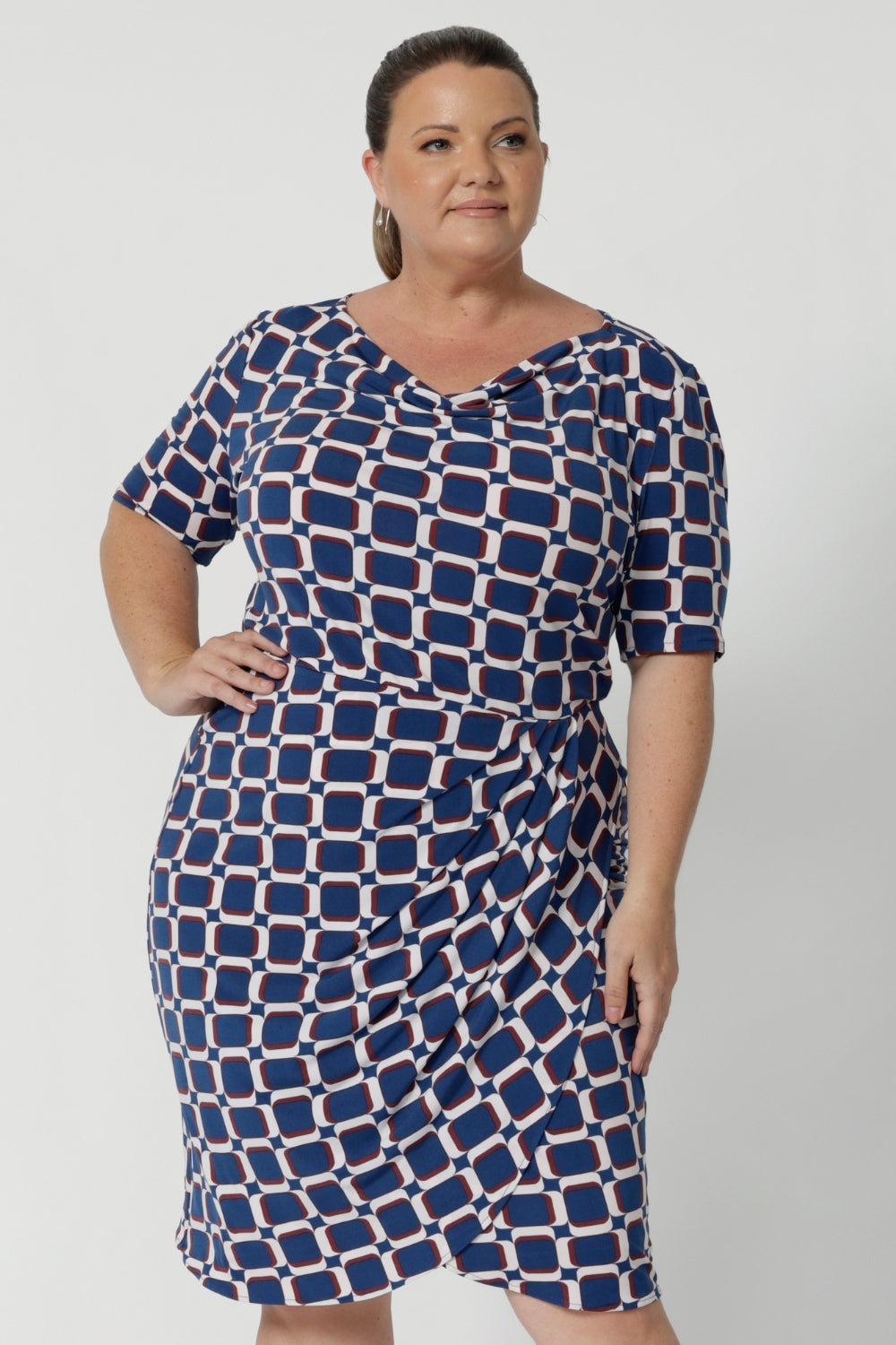 The cowl neckline adds a touch of sophistication and elegance to the design, while the elbow-length sleeves with tuck details at the shoulder provide a unique, refined look. Knee length dress also features subtle stretch at the waist, creating a smooth, defined shape that flatters your figure. Plus size model wears the Imelda Dress in a size 18.