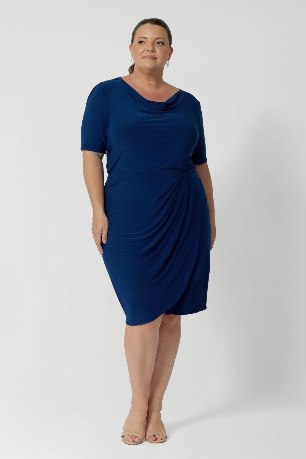 Available in sizes 8-24 and exclusively online at Leina & Fleur, the Imelda Dress is a stylish and comfortable choice for any professional setting. Whether you’re attending meetings, working from the office, or dressing for a business event, this dress will keep you looking chic and confident. Plus size woman wears blue dress with silver accessories and nude heels, creating an elevated workwear outfit.