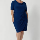 Available in sizes 8-24 and exclusively online at Leina & Fleur, the Imelda Dress is a stylish and comfortable choice for any professional setting. Whether you’re attending meetings, working from the office, or dressing for a business event, this dress will keep you looking chic and confident. Plus size woman wears blue dress with silver accessories and nude heels, creating an elevated workwear outfit.