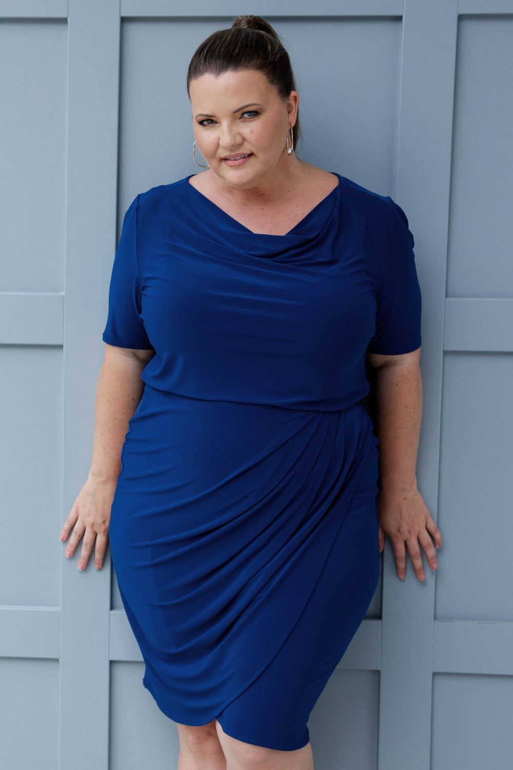 The tulip-shaped wrap skirt with tucks across the front brings an elegant flair, while the semi-fitted design provides just the right amount of structure without feeling restrictive. The dress is unlined, giving it a lightweight feel, and the knee-length hemline offers a polished, professional look that’s perfect for the office. Available in sizes 8-24.