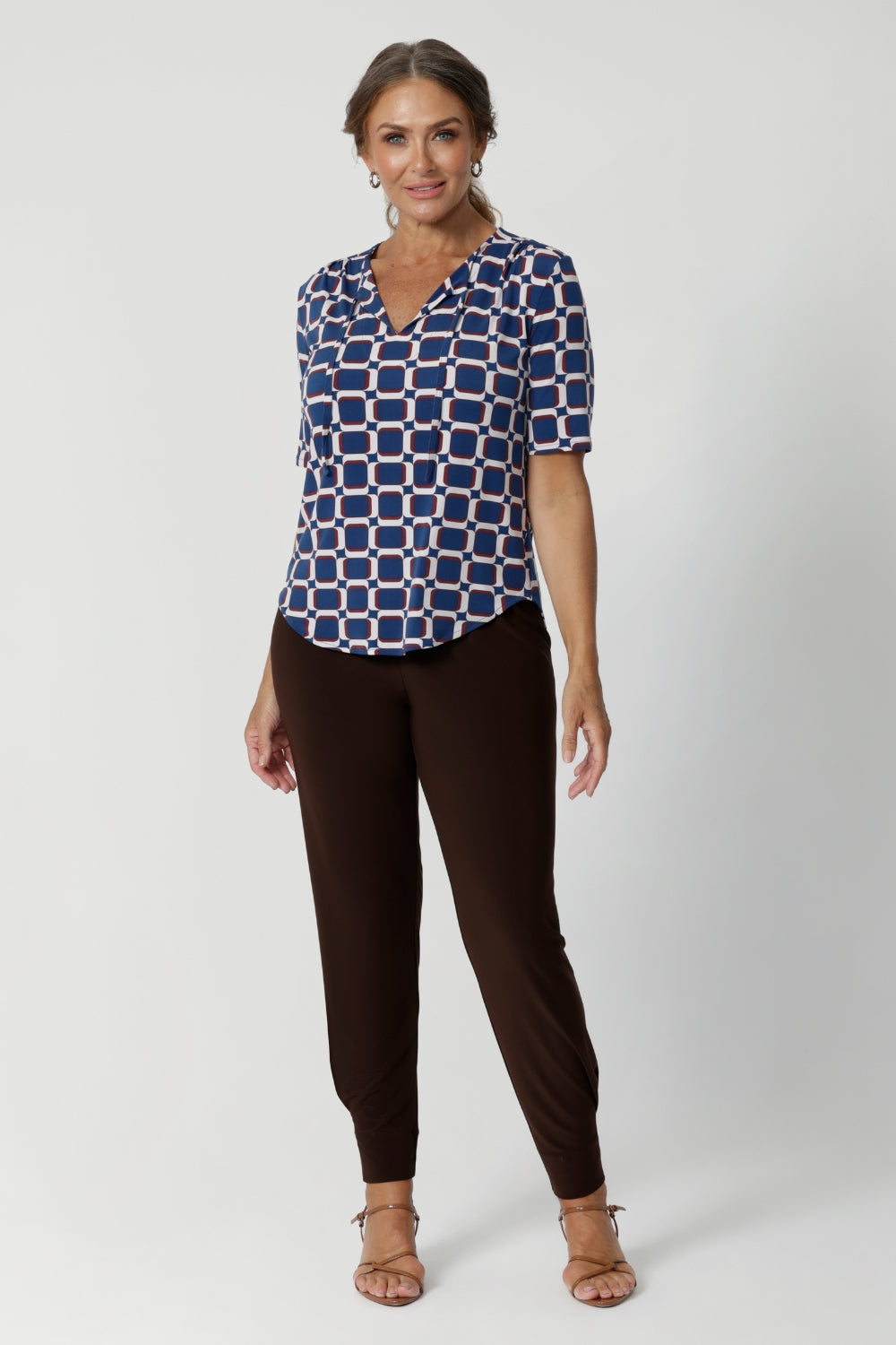 Brown coloured pants for tall, women, these tapered leg, long length pants by Australian and New Zealand women's  clothing brand, Leina & Fleur are comfortable stretchy pants in espresso brown jersey fabric. Worn with a flutter sleeve summer top in blue floral print jersey, these are easy care tall pants for summer style. Shop travel pants for plus size women and ladies tall pants online in sizes 8 to 24.