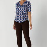 Brown coloured pants for tall, women, these tapered leg, long length pants by Australian and New Zealand women's  clothing brand, Leina & Fleur are comfortable stretchy pants in espresso brown jersey fabric. Worn with a flutter sleeve summer top in blue floral print jersey, these are easy care tall pants for summer style. Shop travel pants for plus size women and ladies tall pants online in sizes 8 to 24.