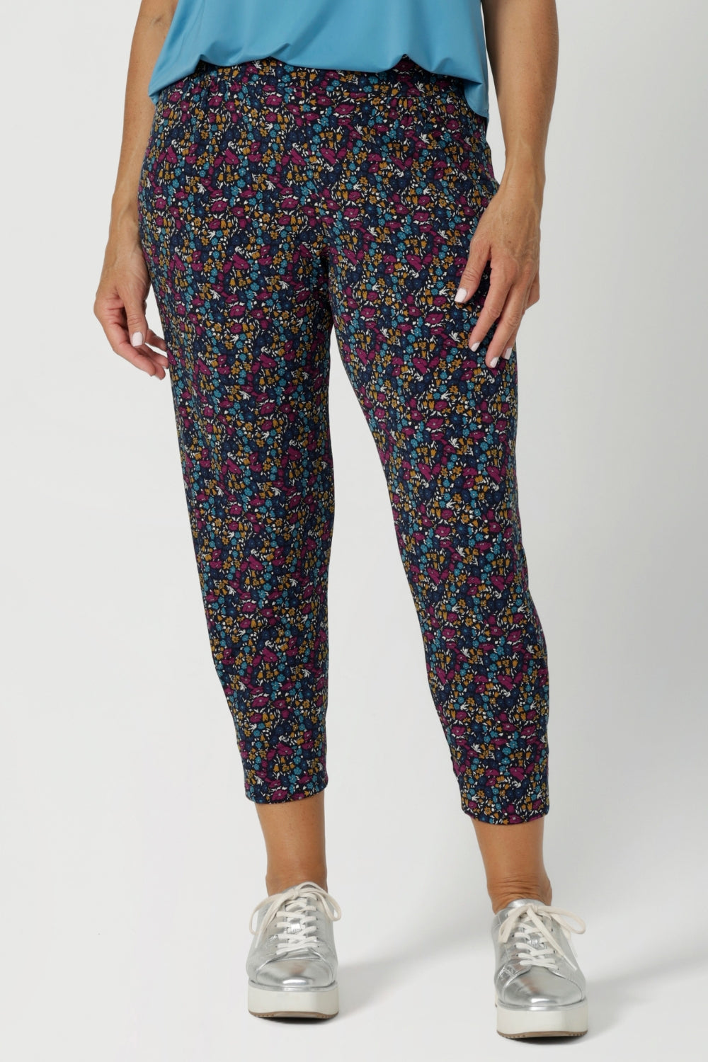 Made from a soft, stretchy fabric with the Harmony print, which features a navy base with vibrant floral details in magenta, mustard, blue, and vanilla, the fabric feels luxurious yet breathable, making it ideal for long days of wear. The mid-rise pull-on waist with a double-layer waistband provides support and comfort, while the front gathers add a touch of sophistication.