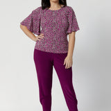 Designed with a mid-rise fit, Indi features a pull-on waist with a double-layer waistband for a smooth and secure fit. The front gathers add a subtle touch of detail, giving the pants a relaxed, flattering look, while the relaxed crotch ensures freedom of movement. Petite woman wears travel ready pants available in sizes 8-24.