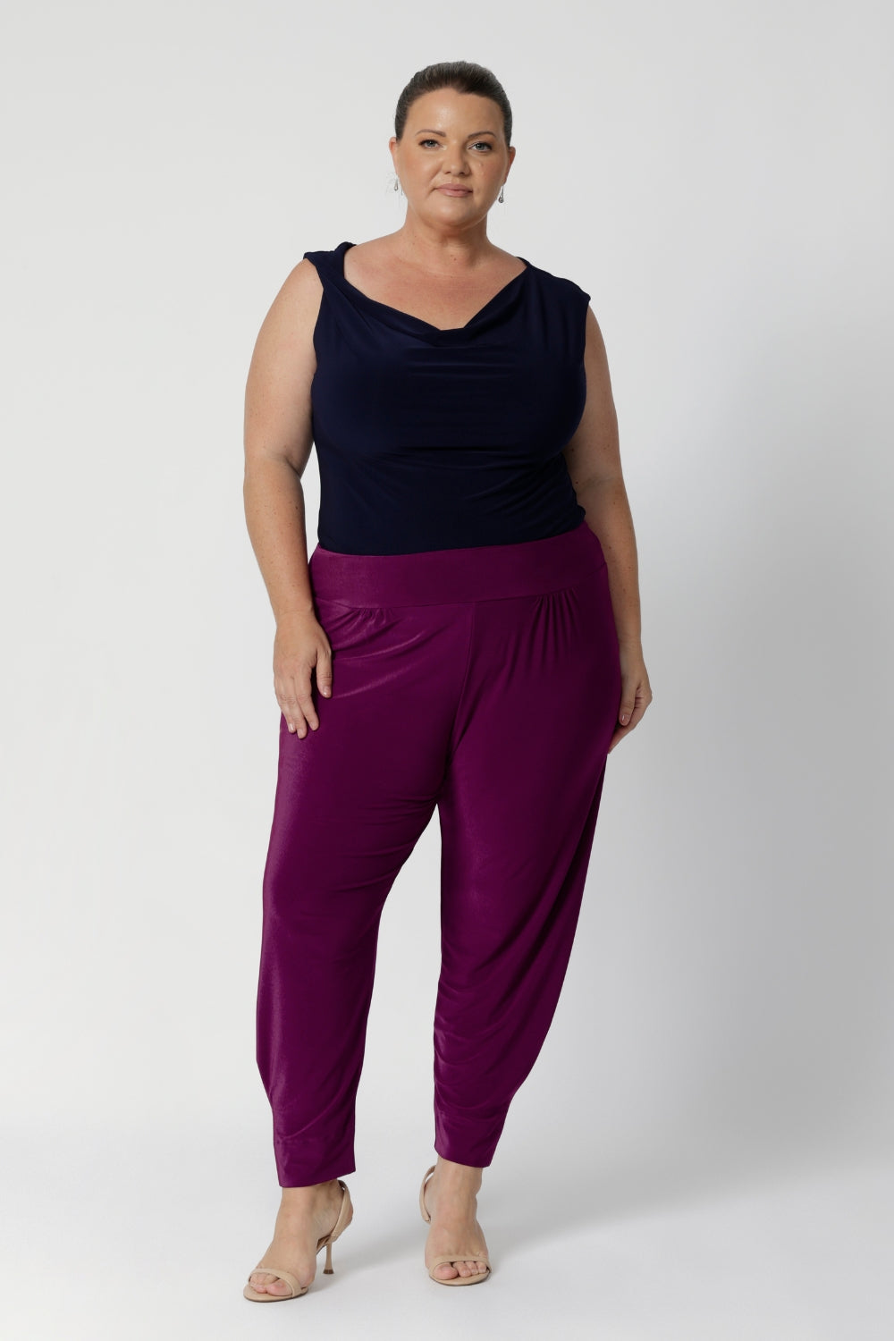 Plus size woman wears tapered leg pants with ankle cuffs, which feature a chic tuck detail for added interest. The 7/8 length is perfect for showing off your favourite shoes, and the pants come in two different lengths to accommodate a variety of heights. Indi Pants in Magenta available in size 8-24 in 2 lengths. 