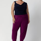 Plus size woman wears tapered leg pants with ankle cuffs, which feature a chic tuck detail for added interest. The 7/8 length is perfect for showing off your favourite shoes, and the pants come in two different lengths to accommodate a variety of heights. Indi Pants in Magenta available in size 8-24 in 2 lengths. 