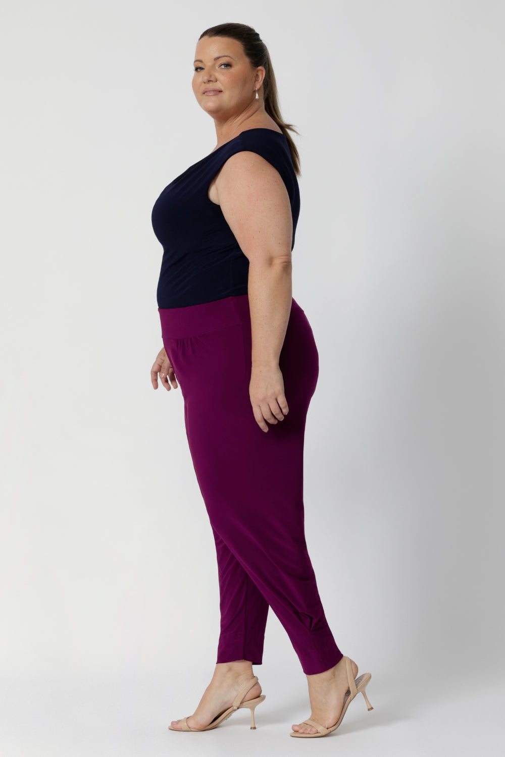 Plus size woman wears Indi Pants in Magenta that feature a tapered leg design. Easy care pants come in two different lengths to accommodate a variety of heights, available in sizes 8-24.