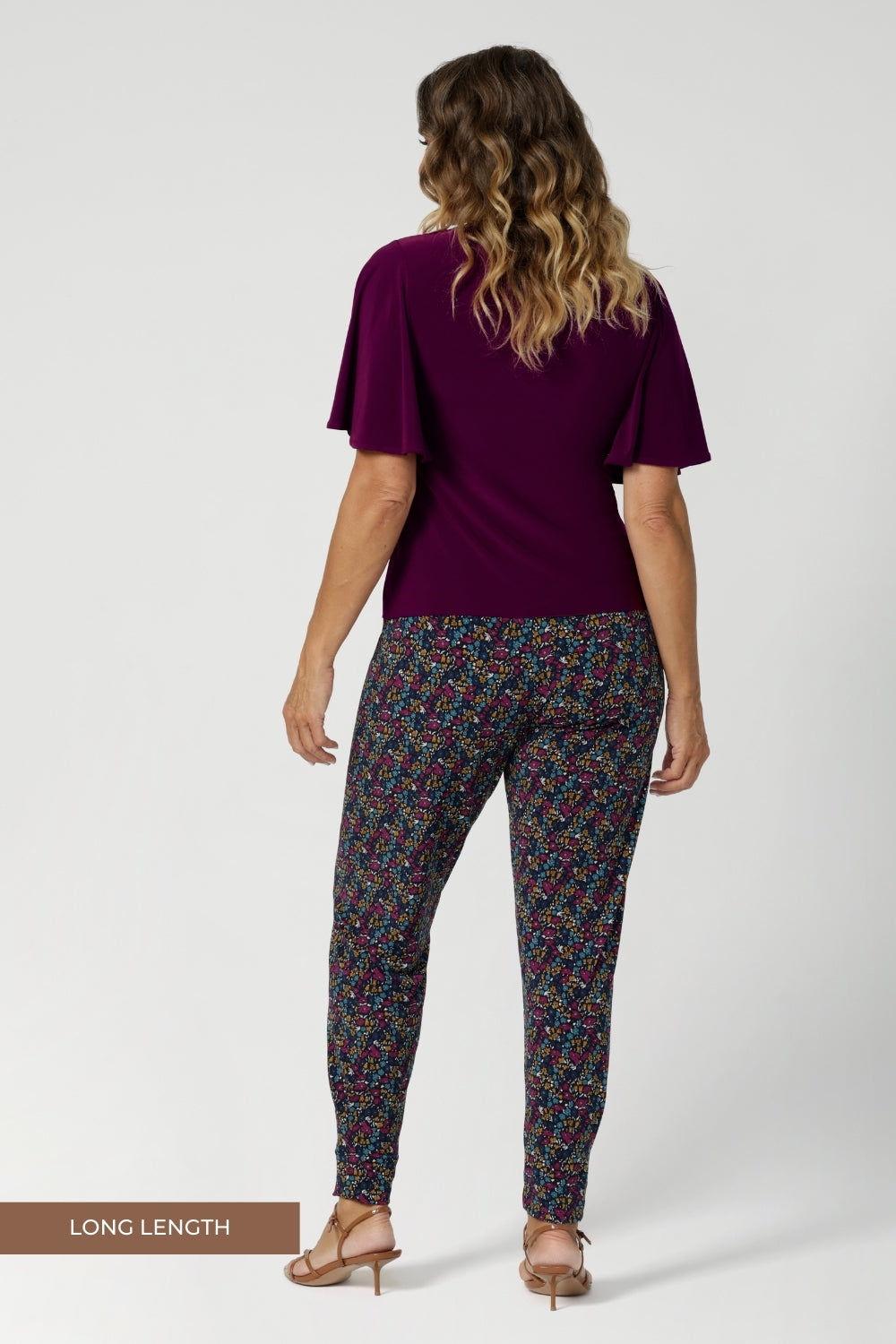 Over 40's women wears long length, pull on style pant, featuring tapered leg and floral print. Travel ready pant is made of light weight dry touch jersey - that is wrinkle resistant and cooling.