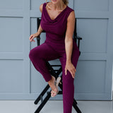 Indi is a stylish and ultra-comfortable pant that’s perfect for both travel and everyday wear. In a vibrant magenta hue, these pants effortlessly combine comfort with modern design, making them a go-to wardrobe staple you'll want in more than one pair. 40 year old woman wears magenta coloured pants with matching cowl neck top, creating a jumpsuit look.