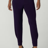 Close up of a size 10 woman wearing the Indi Pant in Amethyst. An Indi pant in amethyst with a mid rise waistband, tapered ankle balloon leg style. A made in Australia pant for women. Perfect travel friendly non-crease pant. Size 8-10.