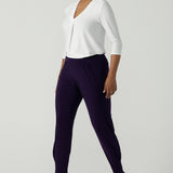 Close up of a size 10 woman wearing the Indi Pant in Amethyst. An Indi pant in amethyst with a mid rise waistband, tapered ankle balloon leg style. A made in Australia pant for women. Perfect travel friendly non-crease pant. Size 8-10.