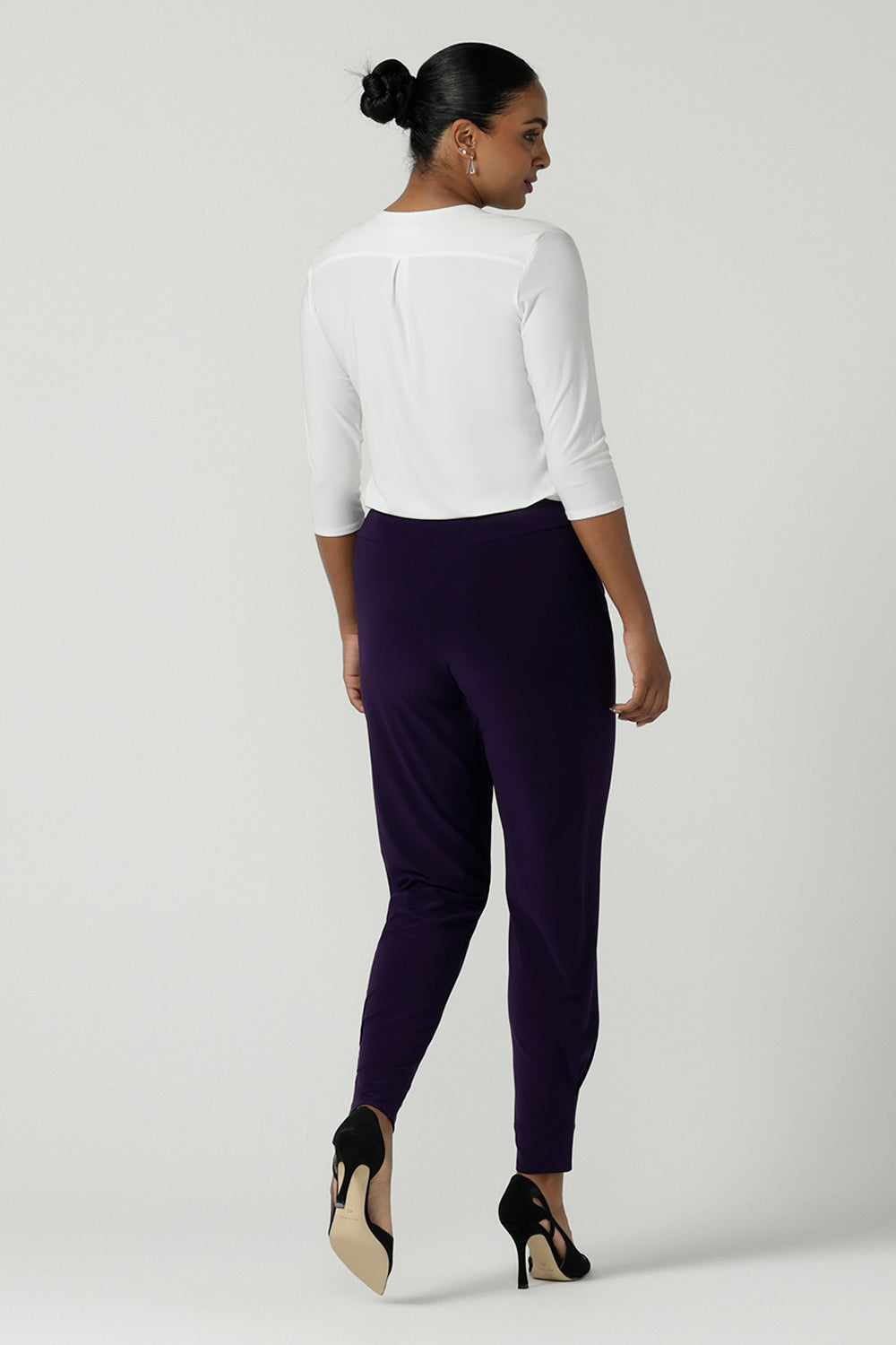 Back view of a size 10 woman wearing the Indi Pant in Amethyst. An Indi pant in amethyst with a mid rise waistband, tapered ankle balloon leg style. A made in Australia pant for women. Perfect travel friendly non-crease pant. Size 8-10.