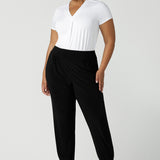 A size 18 curvy woman wears great pants for travel, these dropped crotch, single seam black pants are made stretchy jersey for ultimate comfort. Worn with a white bamboo jersey top , shop these comfy black pants for your travel and capsule wardrobe now!