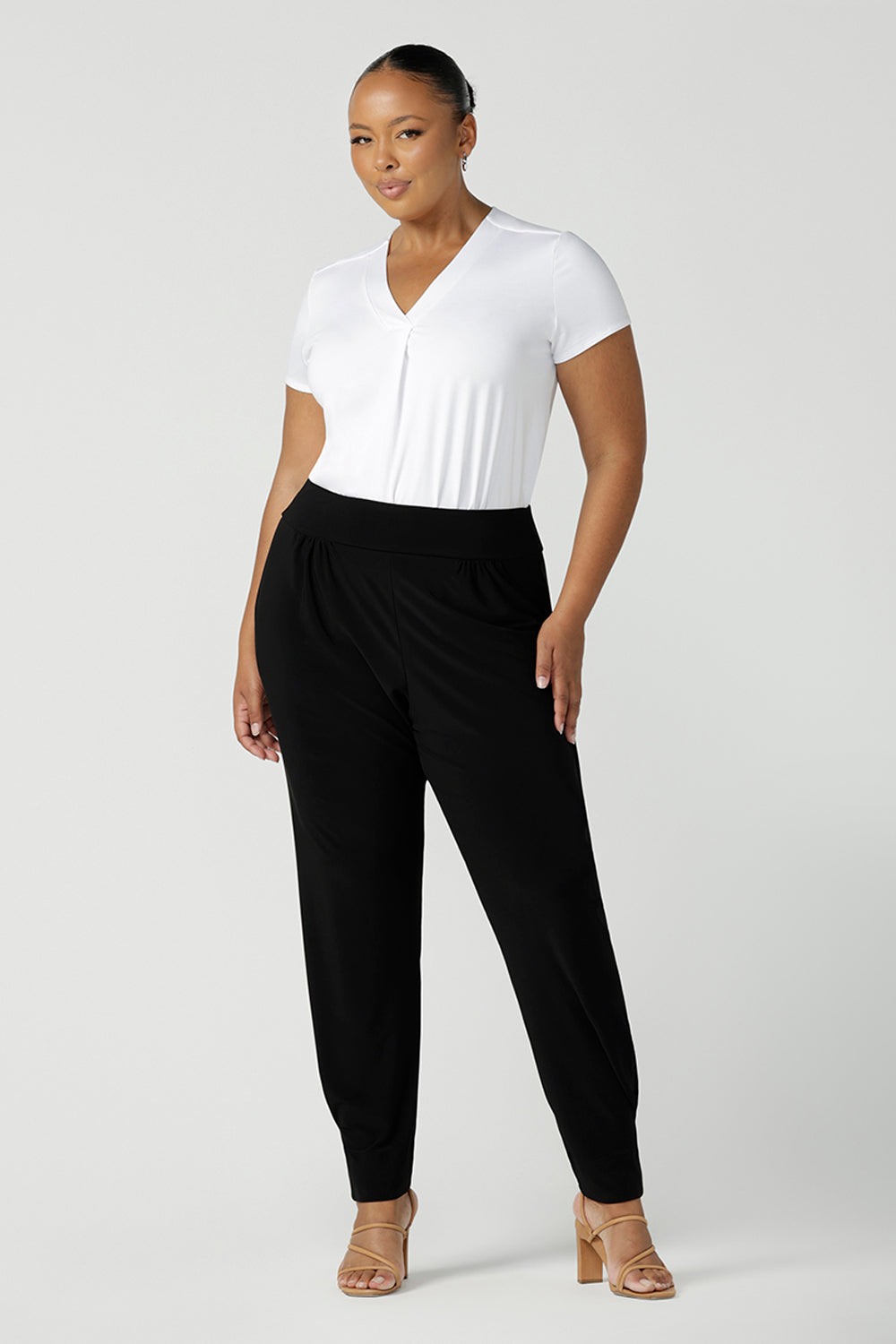 A size 18 curvy woman wears great pants for travel, these dropped crotch, single seam black pants are made stretchy jersey for ultimate comfort. Worn with a white bamboo jersey top , shop these comfy black pants for your travel and capsule wardrobe now!