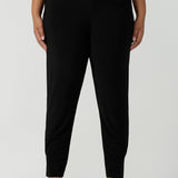 Designed as a full length travel pant for tall women. A size 18 curvy woman wears great pants for travel, these dropped crotch, single seam black pants are made stretchy jersey for ultimate comfort. Worn with a white bamboo jersey top , shop these comfy black pants for your travel and capsule wardrobe now!