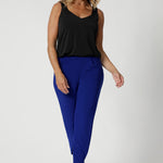Woman over 40 wears travel ready pants in bold cobalt colour. Designed to flatter and fit a range of body types, these pants are available in sizes 8-24, offering a fit that accommodates curves while maintaining a sleek, modern silhouette. They also come in two lengths—regular and long, ensuring that tall women can enjoy a pair of travel pants that fit perfectly, with enough length to provide comfort and coverage. 
