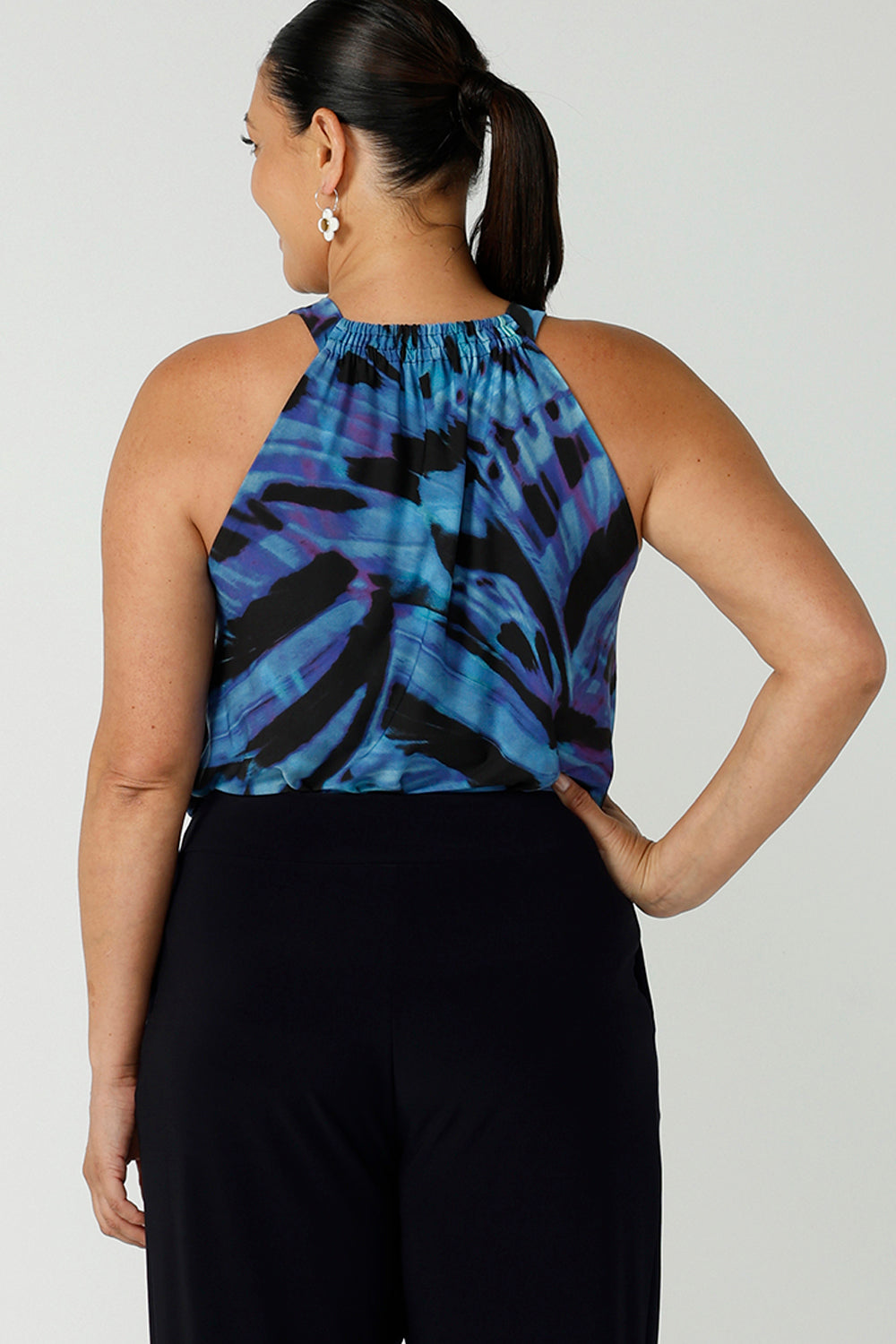 Back view of woman wearing tie neck tie top Iris in Flutter with a blue digital print. Size inclusive clothes for women size 8 - 24. Digital blue and purple print. Made in Australia.