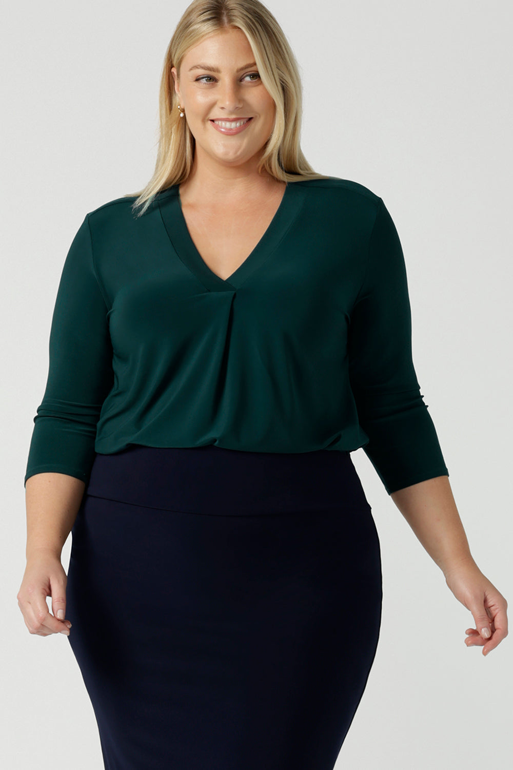 A size 18 woman wears the Jaime Top in Alpine with a soft pleated neckline and 3/4 sleeves. A fitted Andi skirt in Navy. Easy care jersey that is perfect for work to weekend. Made in Australia for  women size 8 - 24. 