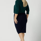 Back view of a size 18 woman wears the Jaime Top in Alpine with a soft pleated neckline and 3/4 sleeves. A fitted Andi skirt in Navy. Easy care jersey that is perfect for work to weekend. Made in Australia for women size 8 - 24. Styled back with black sling back pumps.