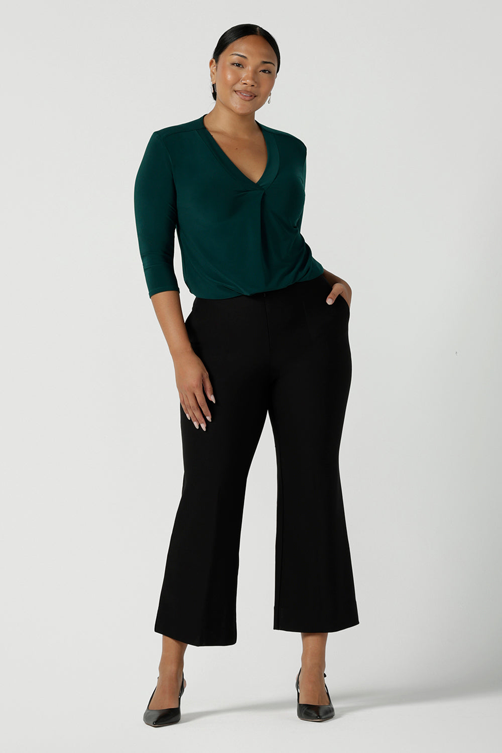 A size 10 woman wears the Jaime Top in Alpine paired back with the Troy pant in Black. The Jaime has a black v-neckline and pleated front with 3/4 sleeves in Alpine jersey. Easy care and great for work to weekend. Made in Australia for women size 8 - 24. 