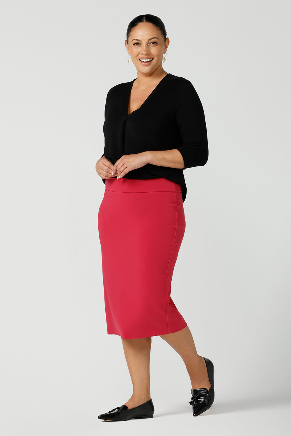 Black Bamboo pleat front top on a size 12 curvy woman. With a 3/4 sleeve and high-low hem, this top is a great women’s work top for corporate wear. Styled back with a fuchsia tube skirt. Designed and made in Australia for women sizes 8 - 24. Leina and Fleur.