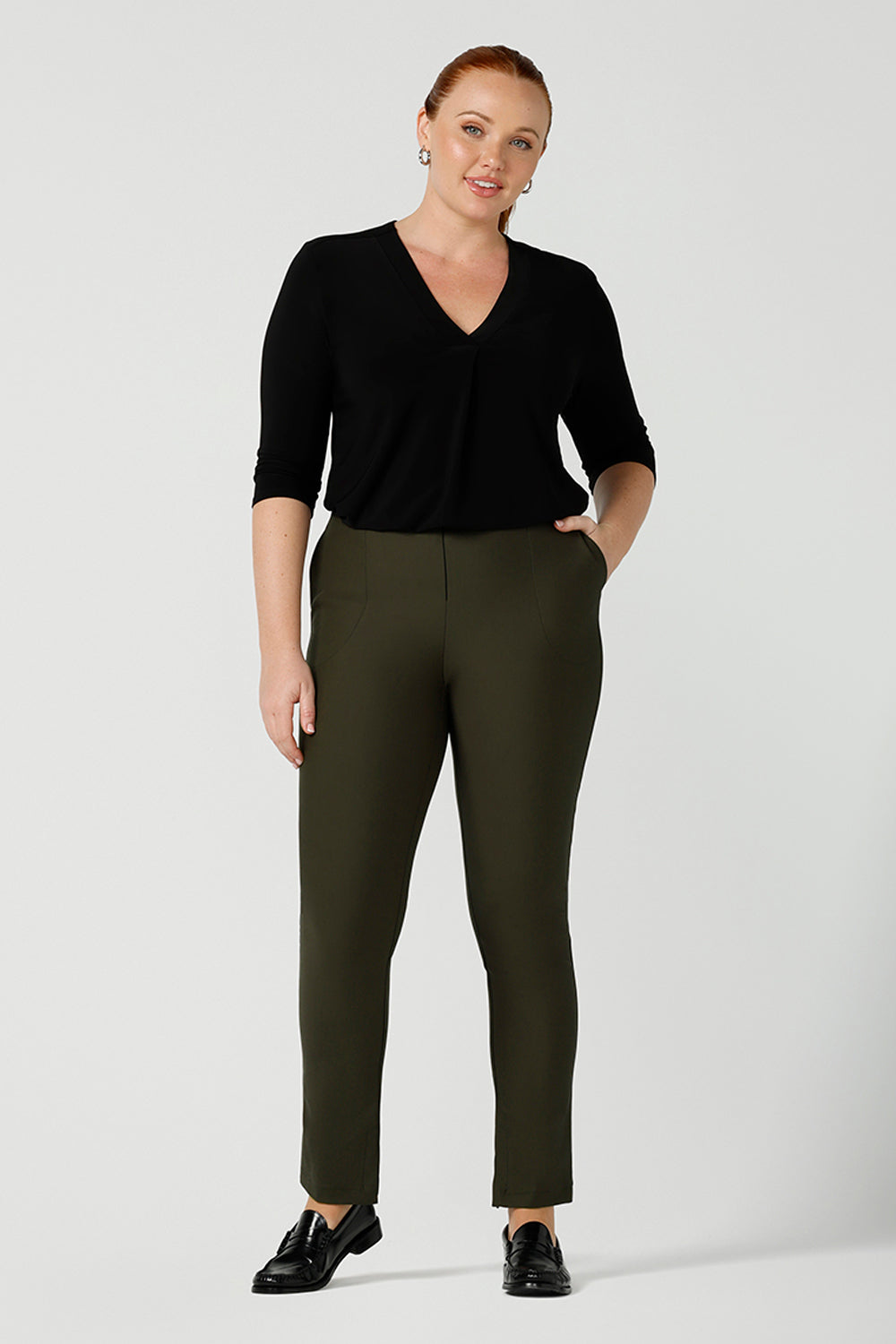 Smart-casual, professional pants for women, these olive green slim leg pants are worn with a V-neck black top with 3/4 sleeves. Made in Australia by online ladies clothing brand, Leina & Fleur shop these comfortable trousers in petite to plus sizes.
