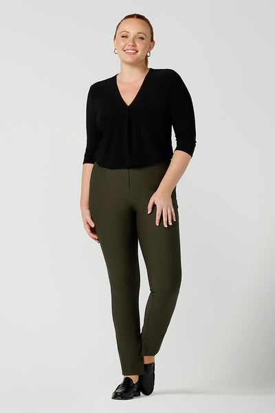 Good smart-casual, professional pants for women, these olive green slim leg, stretch pants are shown with a V-neck black 3/4 sleeve top, on a size 12, curvy woman. Made in Australia by online ladies clothing brand, Leina & Fleur shop these comfortable trousers in petite to plus sizes.