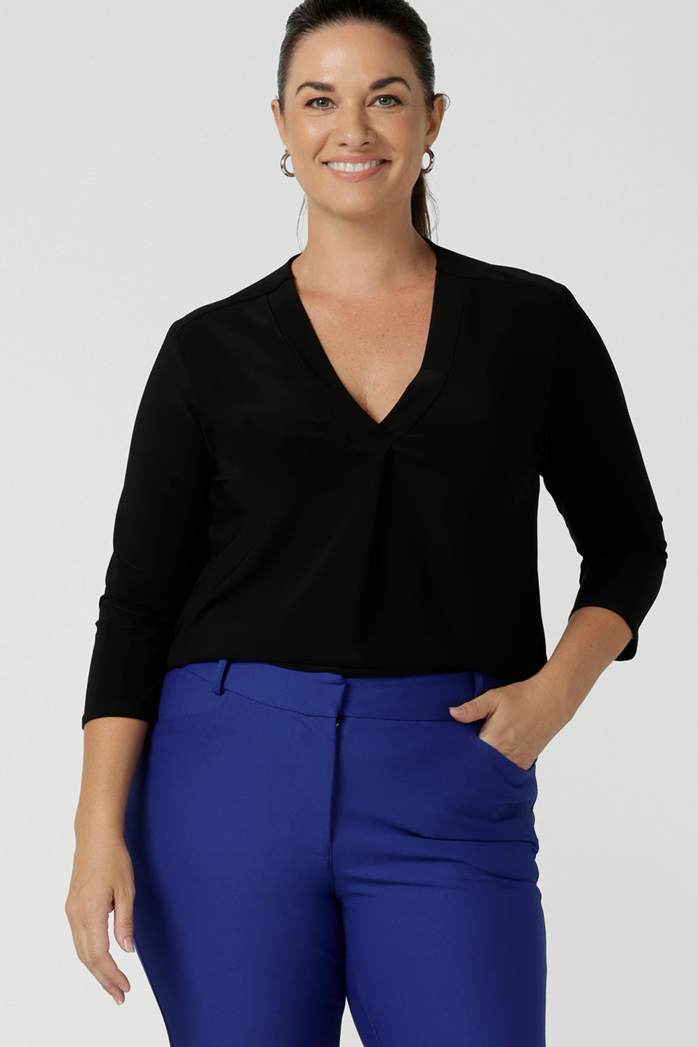 Size 12 woman wears comfortable corporate work top in black jersey. The Jaime top is Australian made with a tailored pleat front neckline, v-neckline and 3/4 sleeve. Sizes 8 - 24