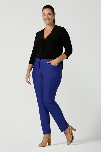 Size 12 woman wears comfortable corporate work top in black jersey. The Jaime top is Australian made with a tailored pleat front neckline, v-neckline and 3/4 sleeve. Styled back with slim fit Cobalt Brooklyn pants. Sizes 8 - 24