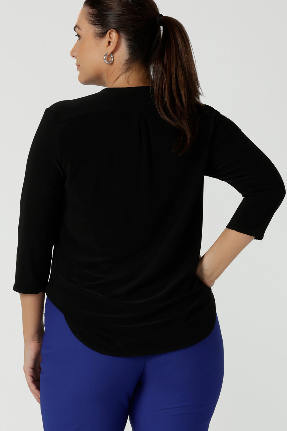 Back view of a size 12 woman wears comfortable corporate work top in black jersey. The Jaime top is Australian made with a tailored pleat front neckline, v-neckline and 3/4 sleeve. Sizes 8 - 24