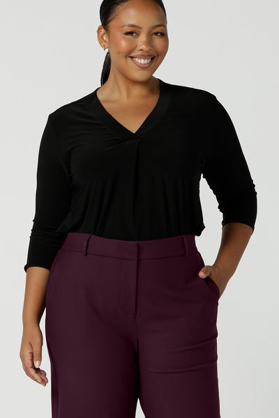 A size 16 curvy woman wears the Jaime top in black.  A comfortable corporate work top with soft tailoring elements like a pleat front neckline, V-neck and 3/4 sleeve. Made in Australia for women size 8 - 24.