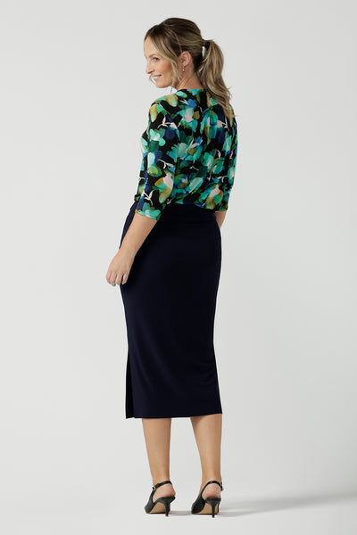 A size 8 woman wears the Jaime top in Canopy with a black base. A beautiful green watercolour print with a black base and a Navy andi skirt. Made in Australia for women size 8 - 24.
