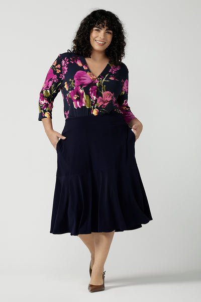 Size 18 woman wears the Jaime Top in Celeste. A comfortable workwear top that is easy care jersey. Featuring 3/4 sleeves and a v-neckline. Made in Australia and size inclusive. Size 8 - 24. Styled back with the Berit Skirt in Navy. 