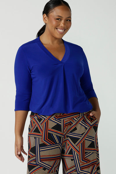 Size 16 Woman wears the Jaime top in Cobalt, a v-neck pleat front top with 3/4 sleeves. Soft Cobalt blue jersey and styled back with black work pants. Made in Australia for women size 8 - 24