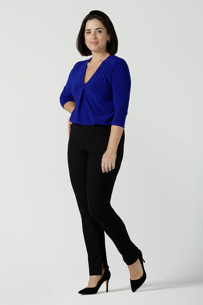 Size 10 Woman wears the Jaime top in Cobalt, a v-neck pleat front top with 3/4 sleeves. Soft Cobalt blue jersey and styled back with black work pants. Made in Australia for women size 8 - 24.
