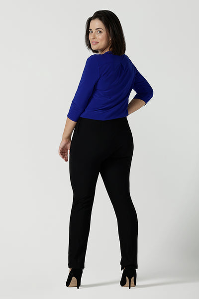 Back view of a size 10 Woman wears the Jaime top in Cobalt, a v-neck pleat front top with 3/4 sleeves. Soft Cobalt blue jersey and styled back with black work pants. Made in Australia for women size 8 - 24.