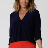 Close up shot of 40 year old woman wearing navy v neck top. This easy care shirt is made from easy care dry touch jersey fabric. Designed in Australia for Australian and New Zealand women. Leina & Fleur is a woman's clothing brand that stock sizes from 8 to 24. Shop this work wear top in black and navy.