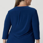 Crafted from a luxurious deep blue dry-touch jersey fabric, this top offers a soft stretch that provides all-day comfort while maintaining a polished, structured look. Plus size woman wears her blue workwear  top in size 18 with wine coloured pants. 