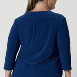 Crafted from a luxurious deep blue dry-touch jersey fabric, this top offers a soft stretch that provides all-day comfort while maintaining a polished, structured look. Plus size woman wears her blue workwear  top in size 18 with wine coloured pants. 