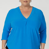 The V-neckline is elevated with a tailored tuck at the center front, adding structure and a refined touch to the design. The 3/4 length sleeves offer just the right amount of coverage, while maintaining a sleek and contemporary look. A center back tailored tuck further enhances the top's polished, tailored appearance, ensuring a flattering shape and clean lines. Size 18 model wears navy pants, matched with opal coloured shirt and silver jewellery.  