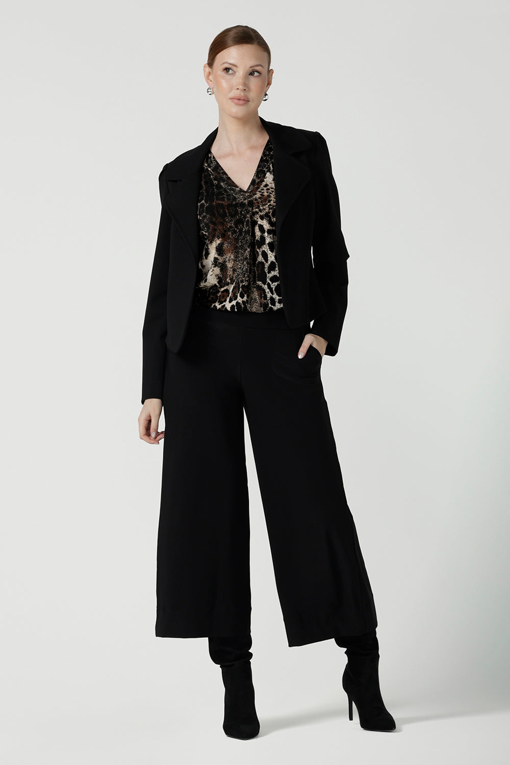 A size 10 woman wears the Jaime Top in Panthera, a jersey animal print top perfect for work to weekend. A v-neck top with 3/4 sleeves. Made in Australia for petite to plus size women size 8 - 24. Styled back with a black jacket. 
