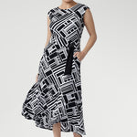 Size 10 woman wearing a black and white geometric patterned dress with matching belt and black kitten heels.