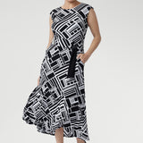 Size 10 woman wearing a black and white geometric patterned dress with matching belt and black kitten heels.