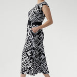 This sleeveless dress is a standout choice for summer days, office wear, or weekend outings, blending timeless style with modern versatility. Size 10 women wears black and white dress with matching belt and kitten heels.