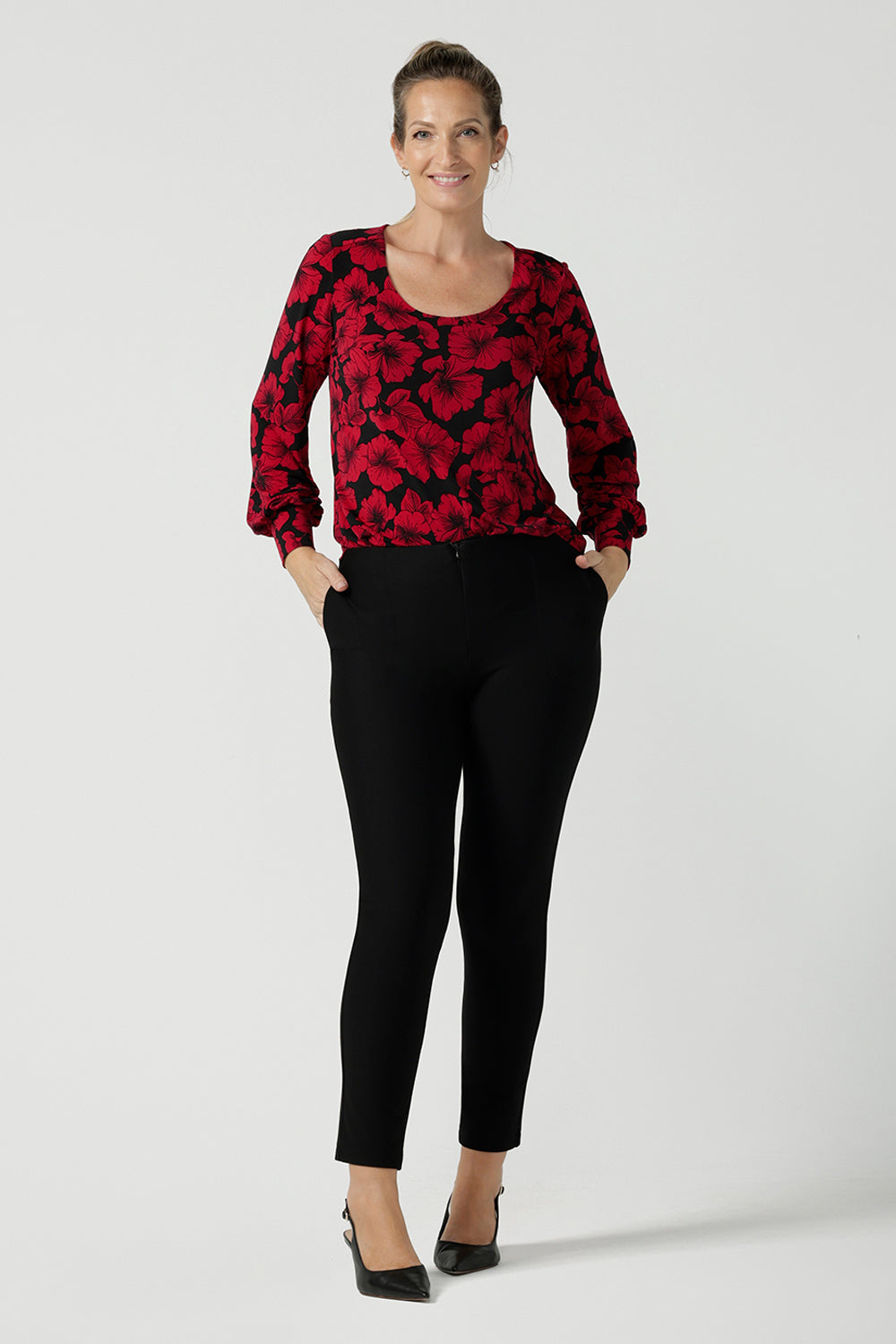 Size 10 woman wears the scoop neck bold poppy top with balloon sleeves. Curved hemline and cuffed sleeves. Made in Australia for women size 8 - 24. Styled back with the Brooklyn pant in black a skinny leg comfortable corporate work pant. 
