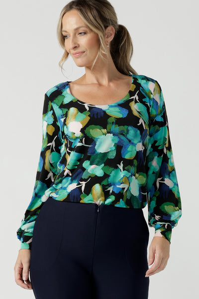 A size 8 woman wears the Jasper top in Canopy. A jersey style in a watercolour green print with balloon sleeves and cuff detail. Round neckline. Styled back with Navy Brooklyn pant in Navy. Made in Australia for women size 8 - 24. 