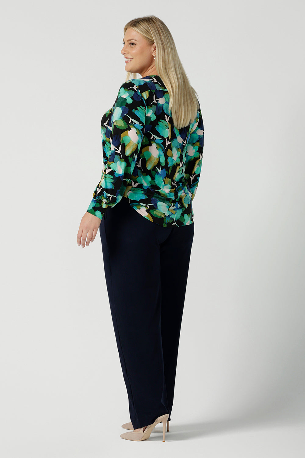 Back view of a size 18 woman wears the Jasper top in Canopy. A jersey style in a watercolour green print with balloon sleeves and cuff detail. Round neckline. Styled back with Navy Brooklyn pant in Navy. Made in Australia for women size 8 - 24.
