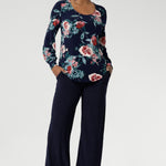 Crafted from a premium dry-touch jersey with soft stretch, the Vintage Rose print blooms across a deep navy base, with floral accents in pink, red, and blue. Designed and made in Australia for women in sizes 8 to 24. Size 10 model wears her blouse untucked over navy work pants.