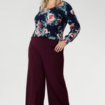 Feminine, flattering, and thoughtfully designed, the Jasper Top in Vintage Rose is a versatile staple made to elevate your everyday style. Plus size woman wears her Jasper Top tucked into wine coloured trousers.